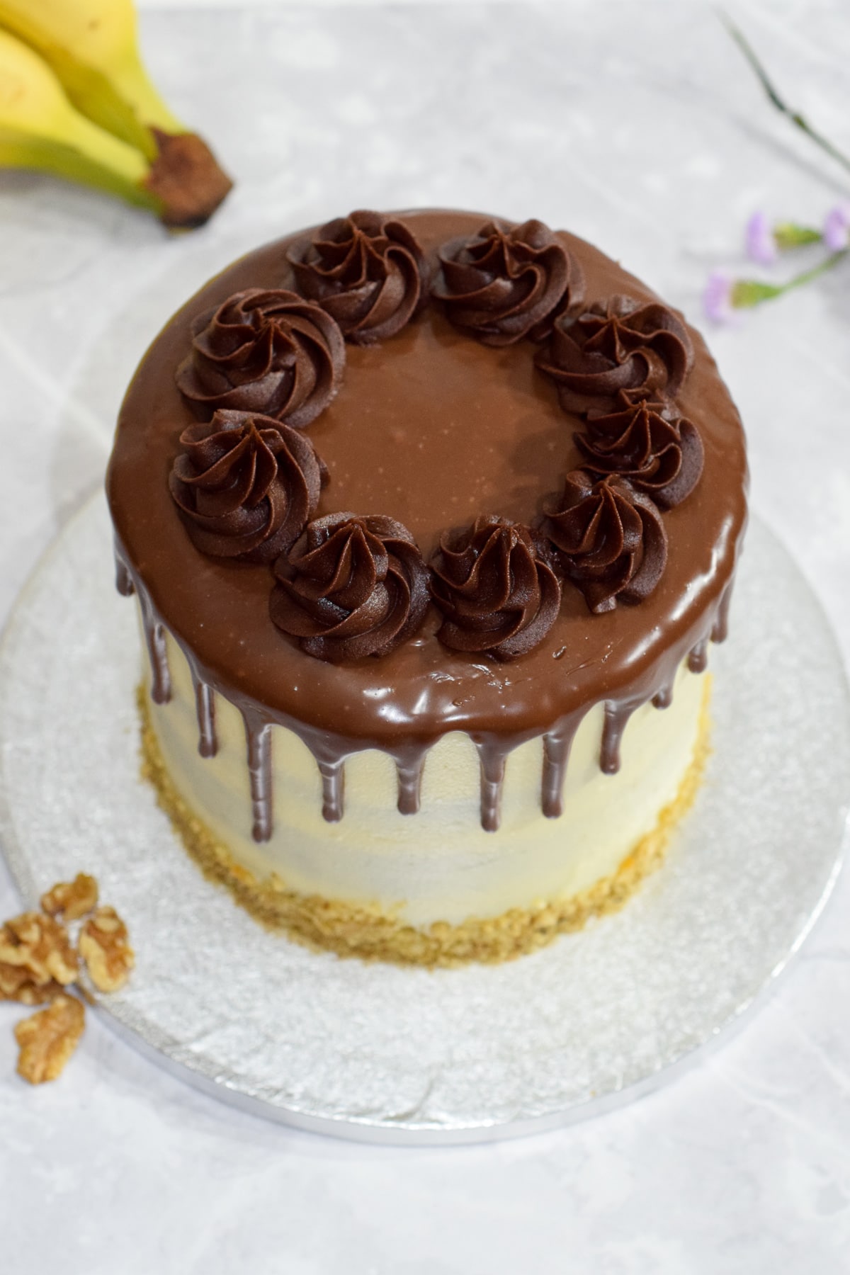 Banana walnut cake with vanilla cream cheese frosting and a milk chocolate ganache drip