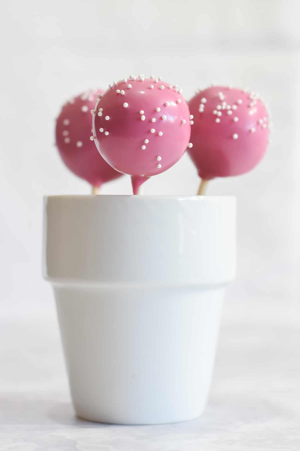 Pink Starbucks copycat vanilla birthday cake pops with white mini pearl sprinkles in cup
