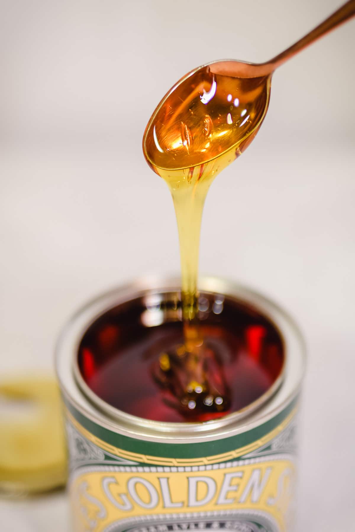 golden syrup dripping off spoon into tin
