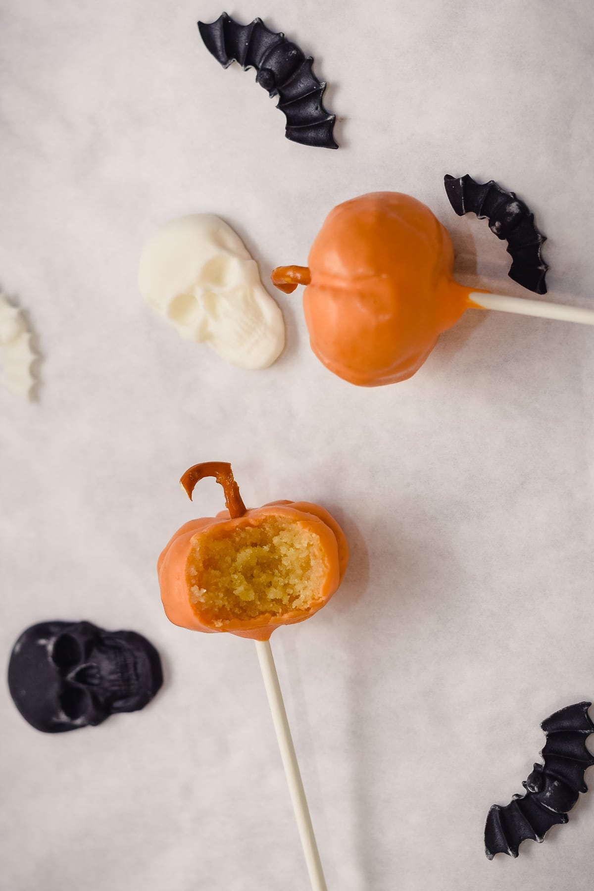 Pumpkin cake pops showing inside of one with Halloween decorations around