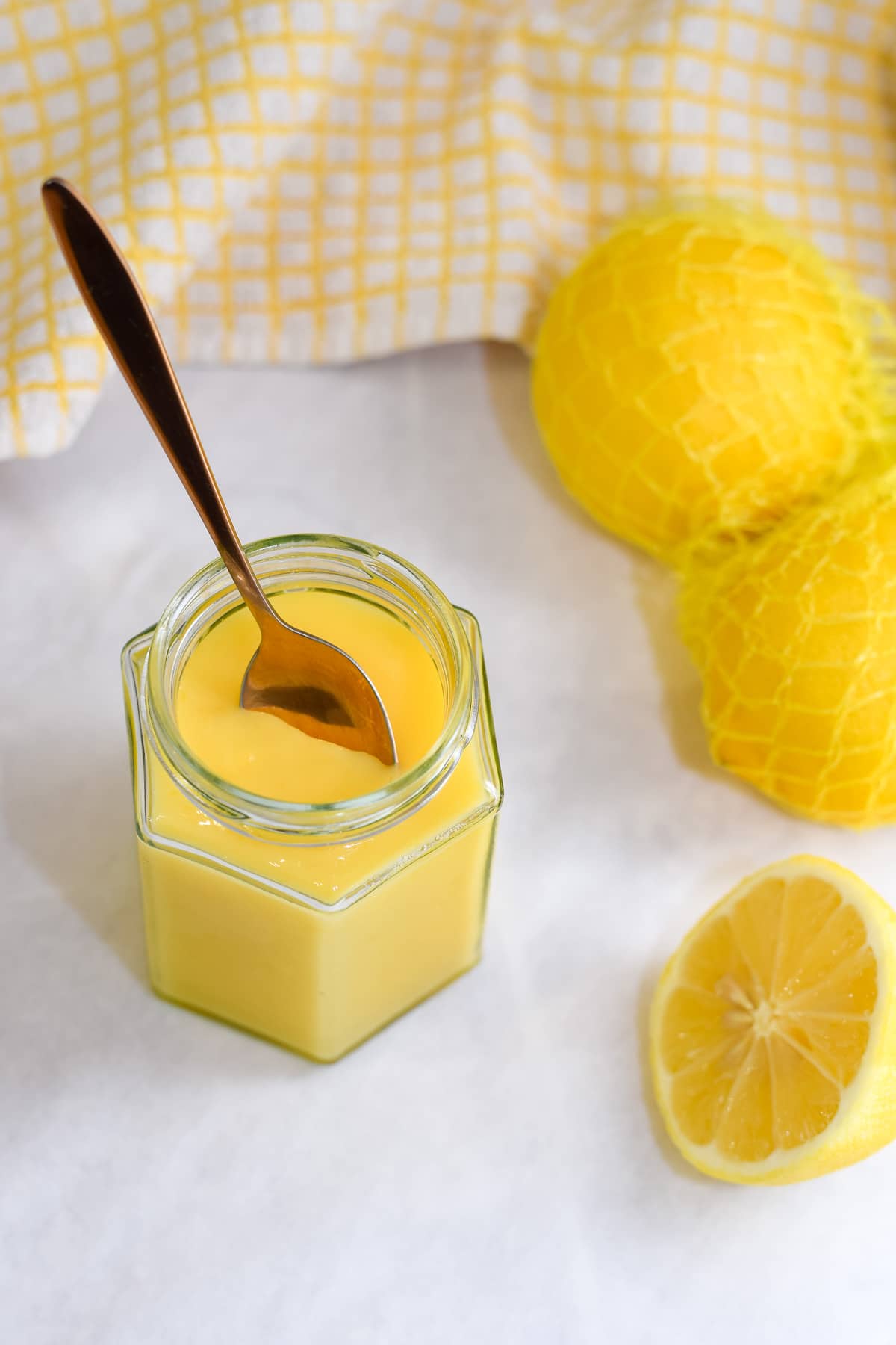 lemon cake in a jar with a spoon and lemons to the side