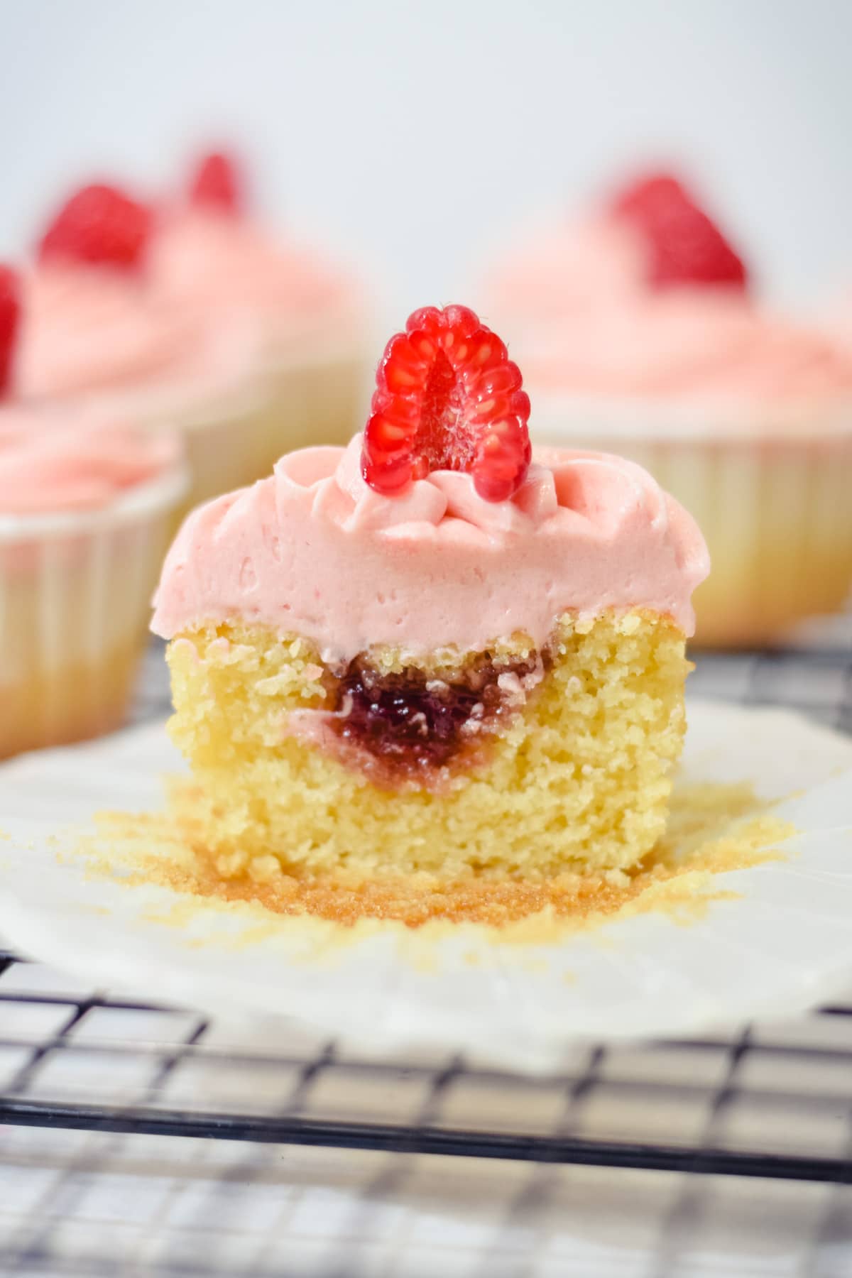 Raspberry cupcake cut in half to show optional raspberry preserves filling