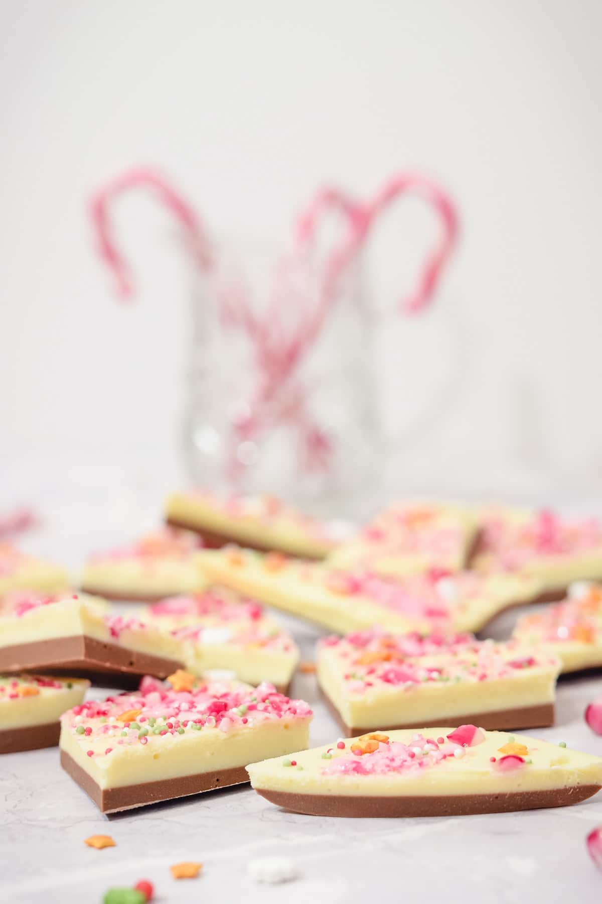 White chocolate peppermint Christmas bark pieces with candy canes in a jar