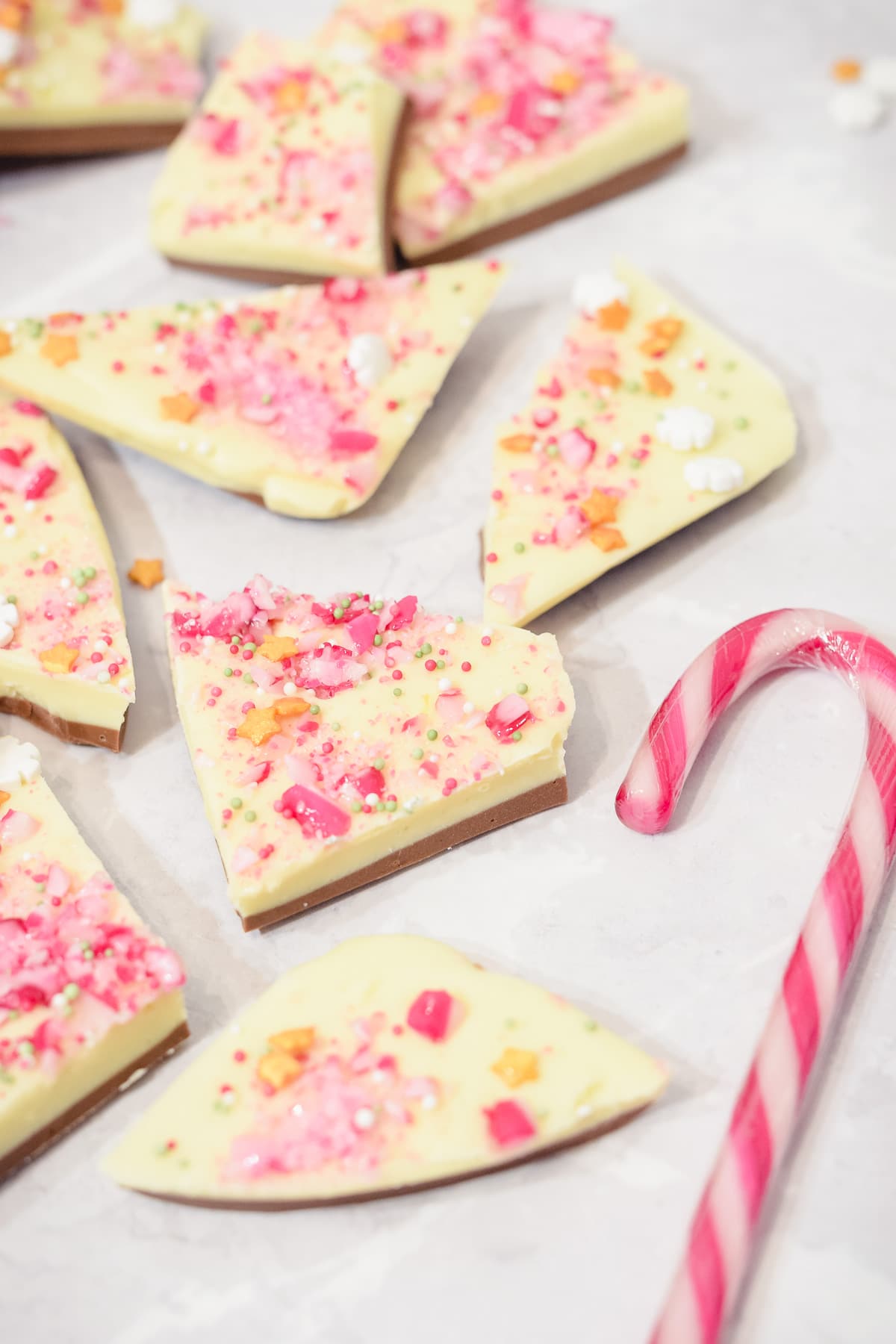 White chocolate peppermint Christmas bark pieces spread out with a candy cane
