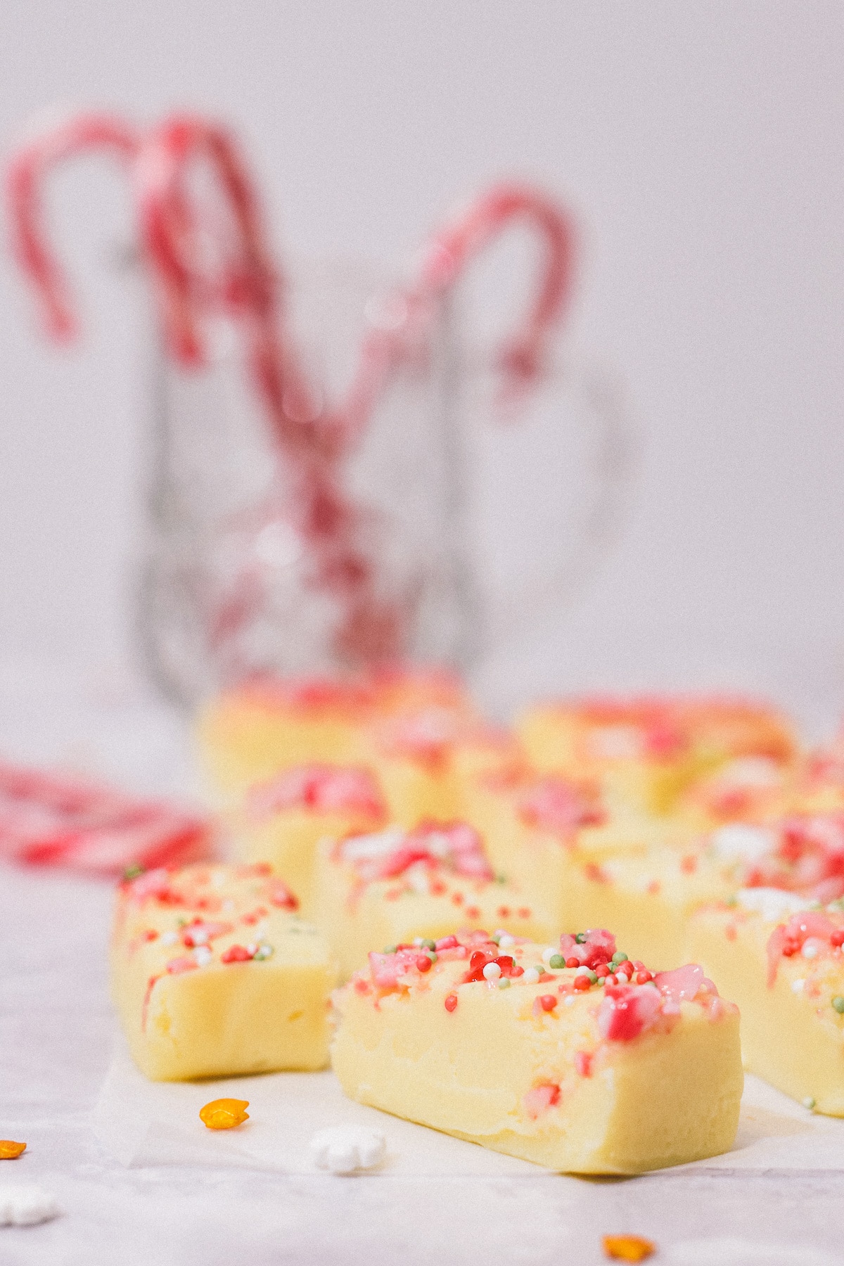 White Chocolate Peppermint Christmas fudge pieces with candy canes in jar behind