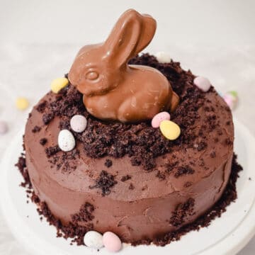 Easter chocolate bunny rabbit sitting in a muddy hole made of chocolate cake and chocolate frosting with mini eggs decorating it