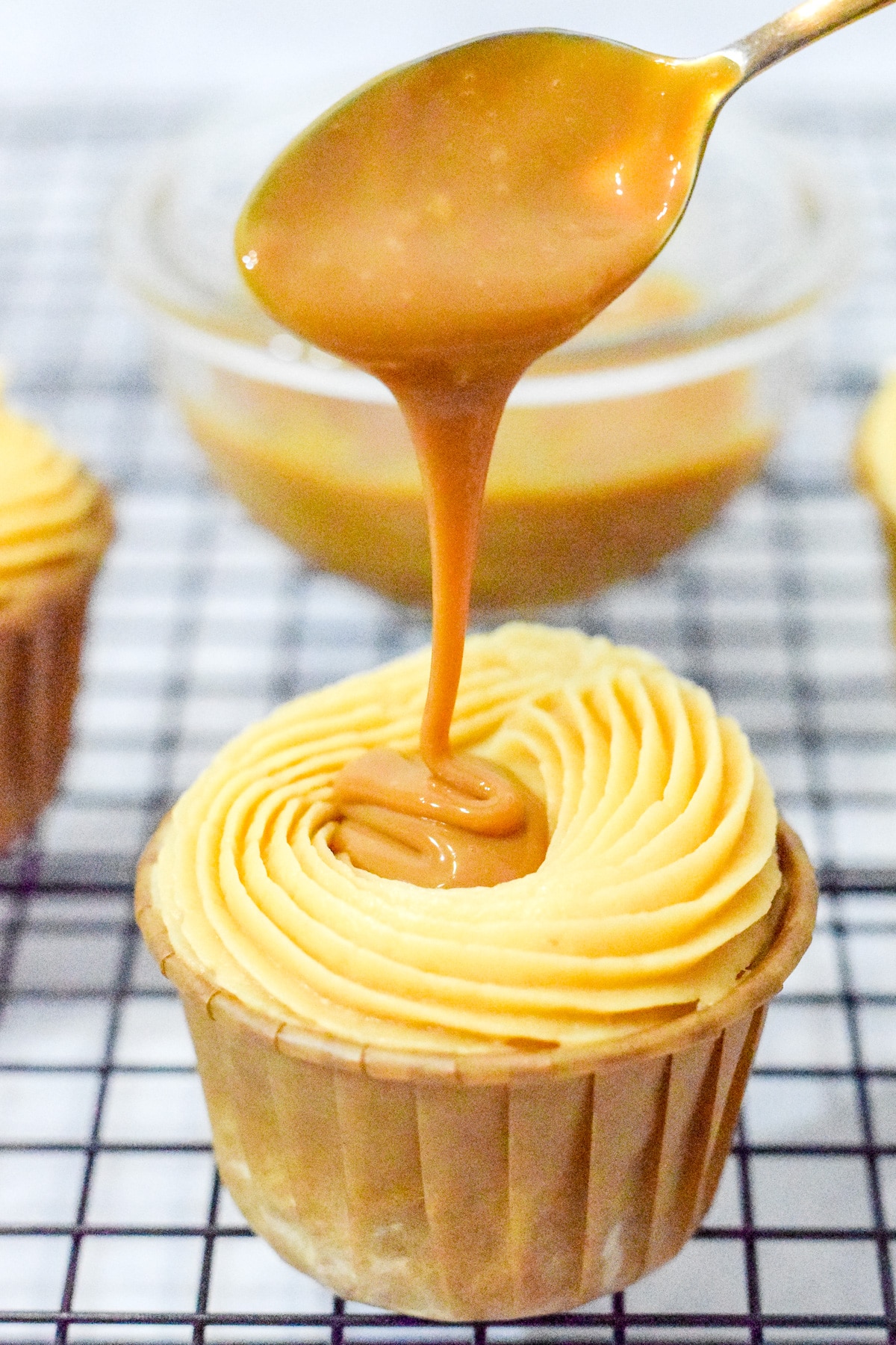 salted caramel whiskey cupcakes with whisky caramel sauce drizzling off a spoon into the cupcake