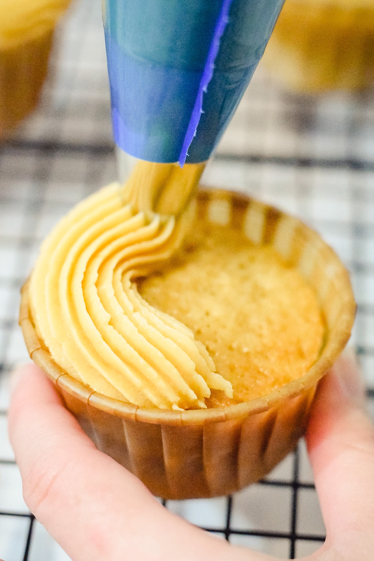 caramel buttercream being piped onto a brown sugar cupcake