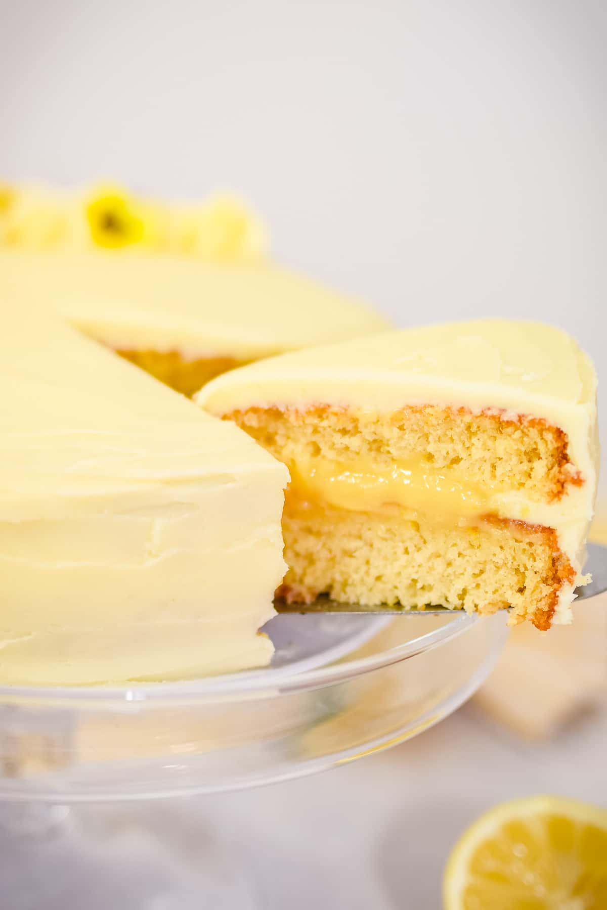 lemon curd cake on a cake stand with a slice taken out showing the curd filling