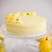 lemon curd cake on a cake stand with lemon curd and lemons