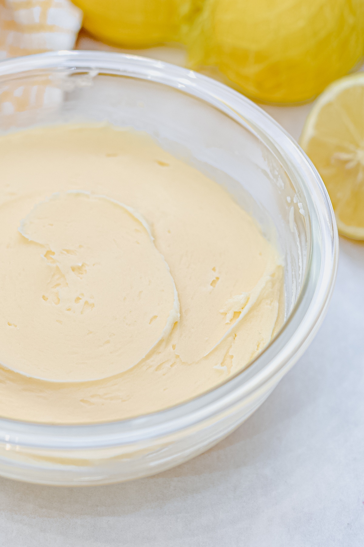easy lemon buttercream frosting in a mixing bowl with lemons behind