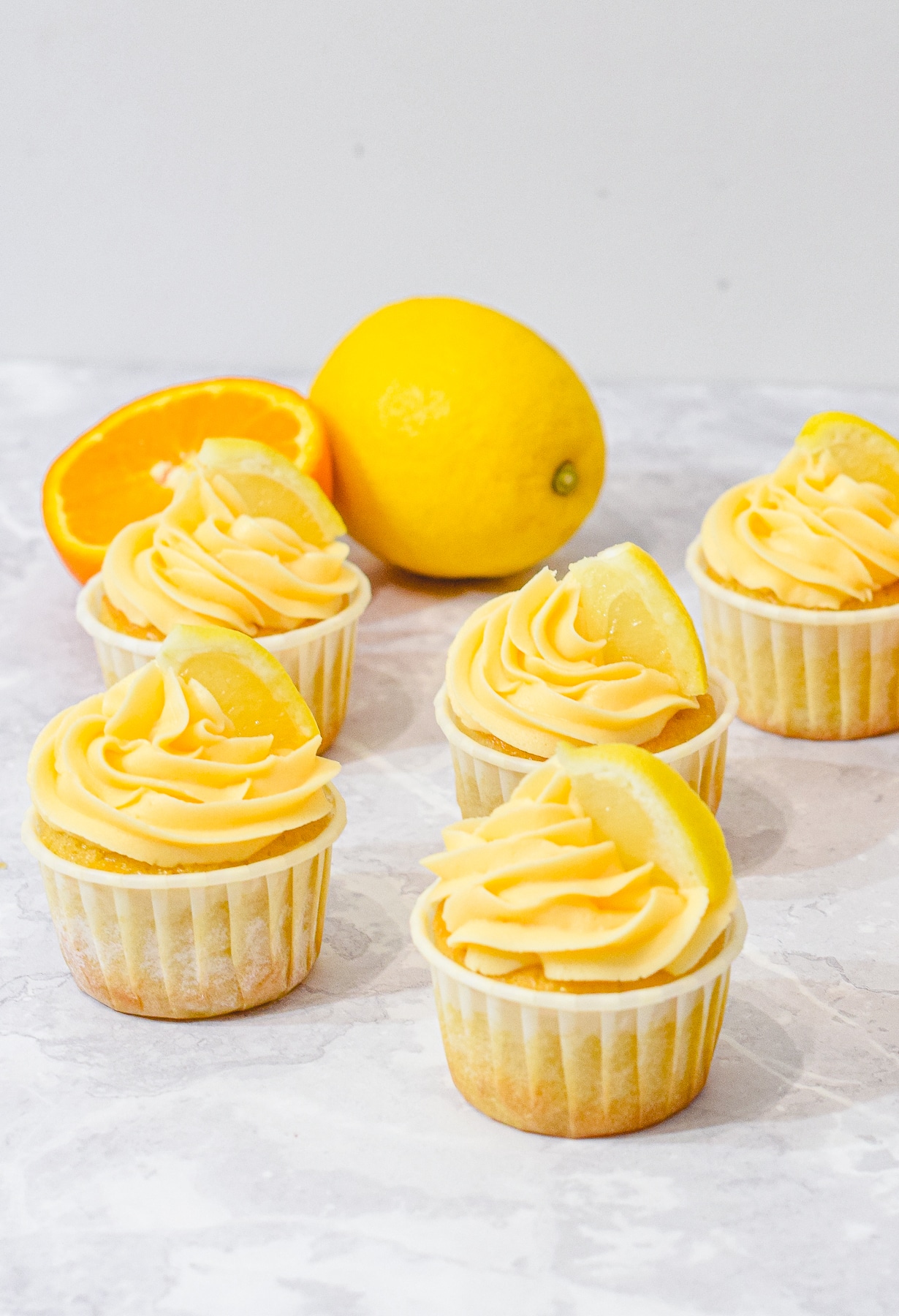 lemon orange cupcakes with orange buttercream frosting swirls and a lemon slices