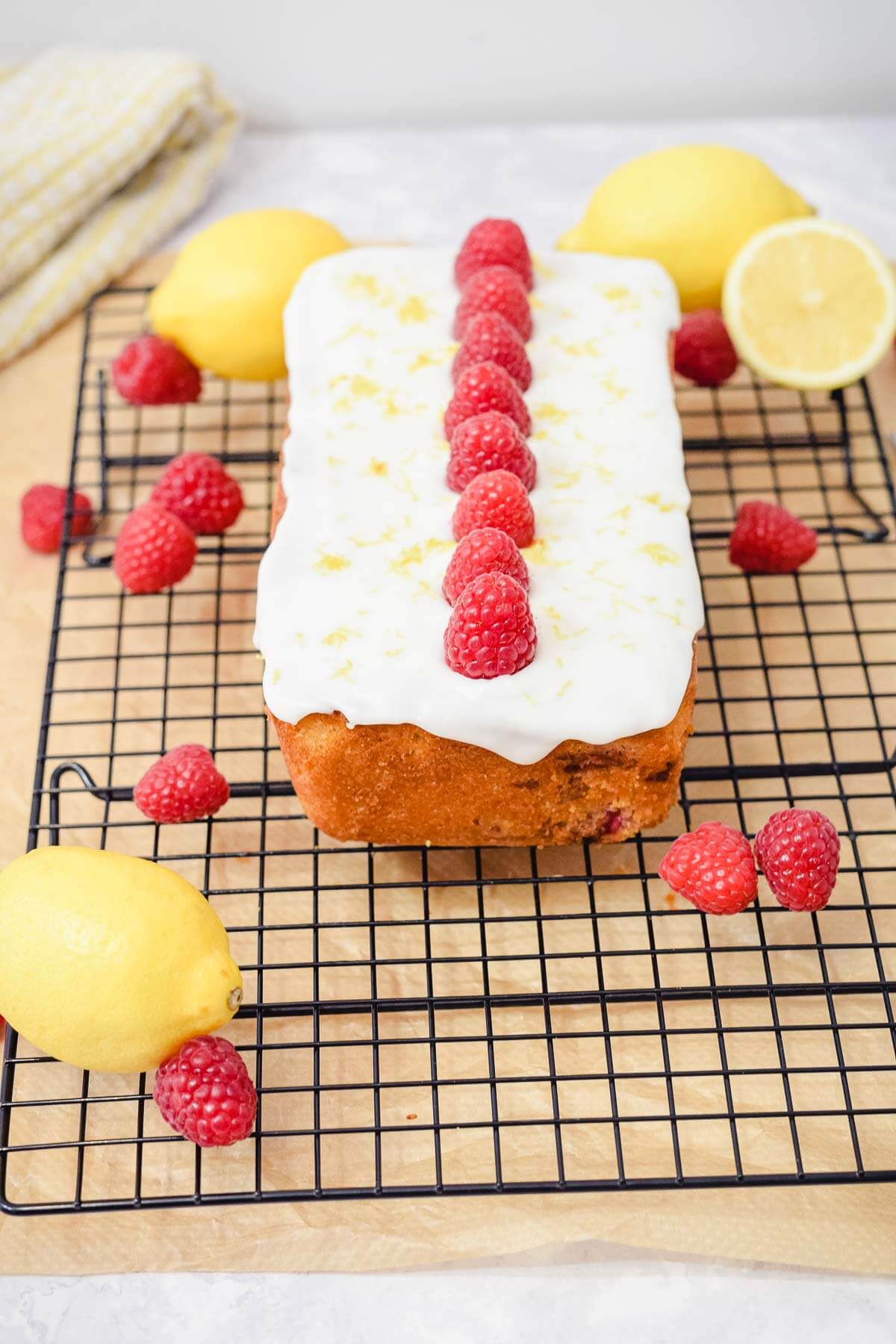 lemon raspberry loaf quick bread with lemon icing and fresh raspberries on a rack