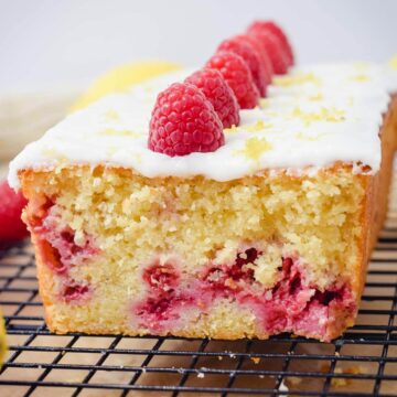 lemon raspberry loaf pound cake sliced topped with lemon glaze and fresh raspberries
