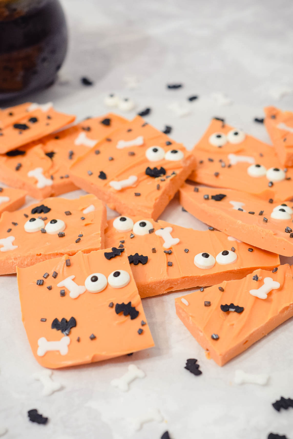orange halloween bark with edible eyes and Halloween sprinkles broken into pieces with a side view.