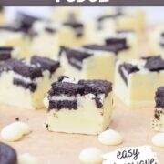 stacked cookies and cream oreo fudge pieces with Oreos on top and white chocolate chips.