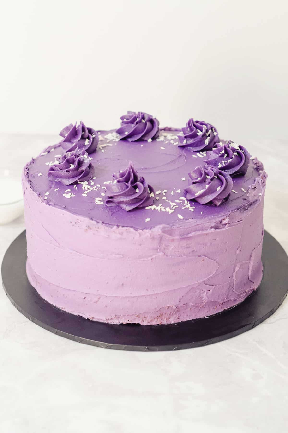 purple yam ube sponge cake with purple ube frosting and shredded coconut topping.