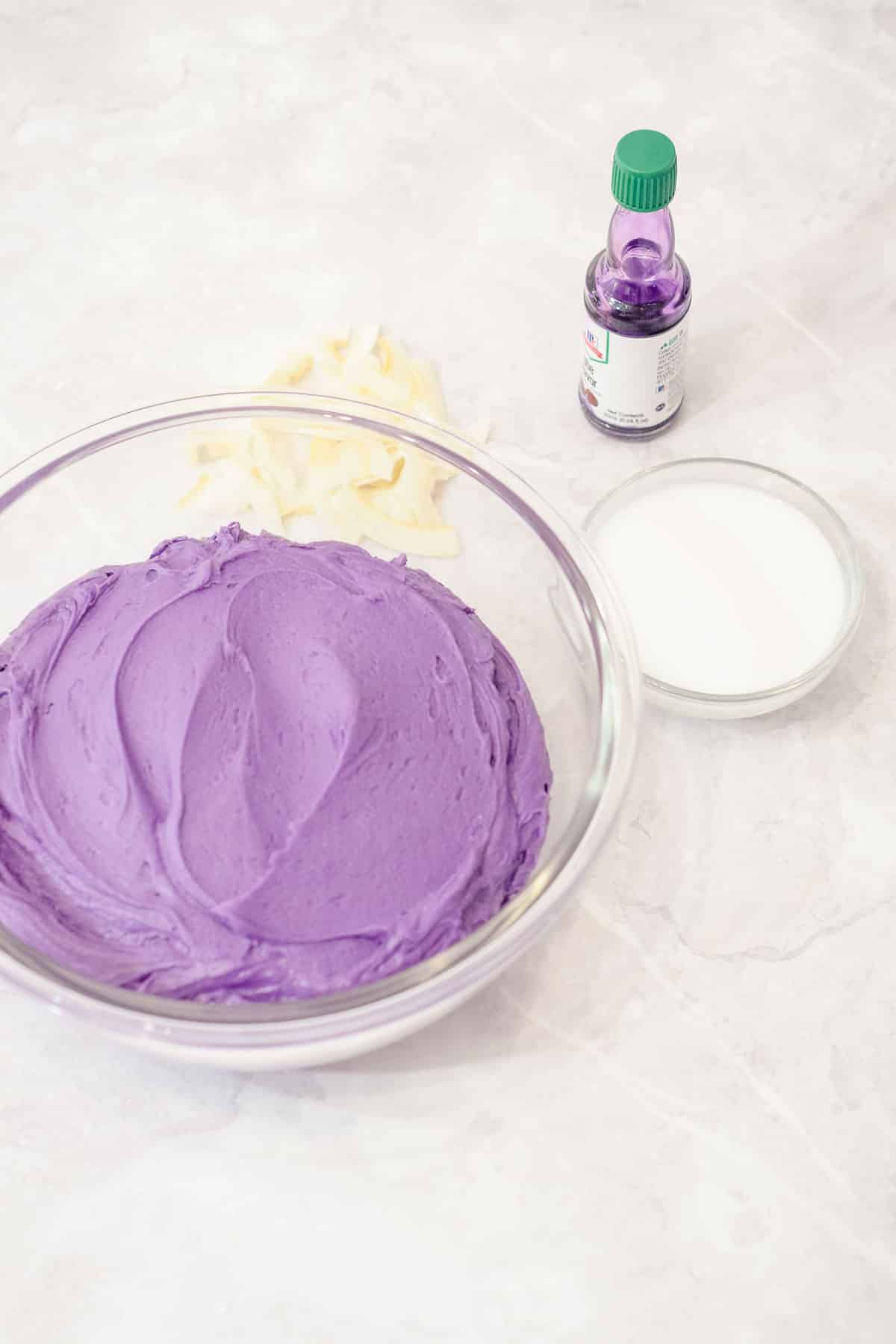 purple yam ube buttercream frosting in a bowl with coconut milk and ube extract
