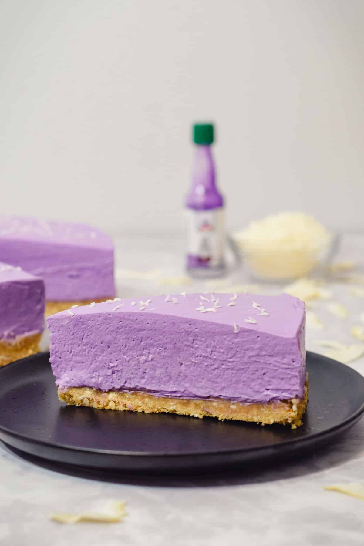 slice of purple ube cheesecake with a coconut cookie base and shredded coconut on top with ube extract.