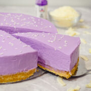 purple ube cheesecake with a coconut graham cracker base and shredded coconut topping with ube extract.