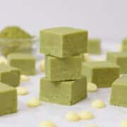 stack of green tea matcha fudge pieces with white chocolate chips and a bowl of matcha powder.