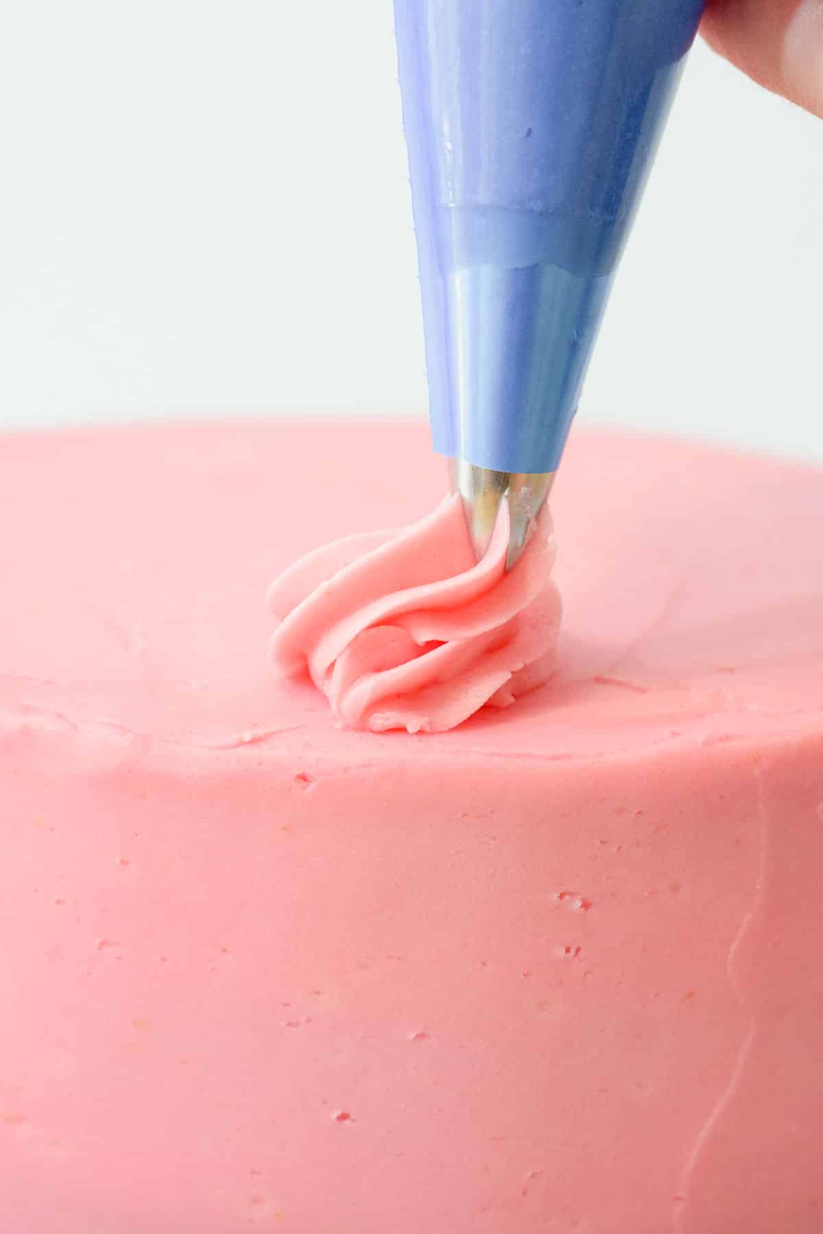 baby pink frosting buttercream icing piped onto a pink buttercream cake.