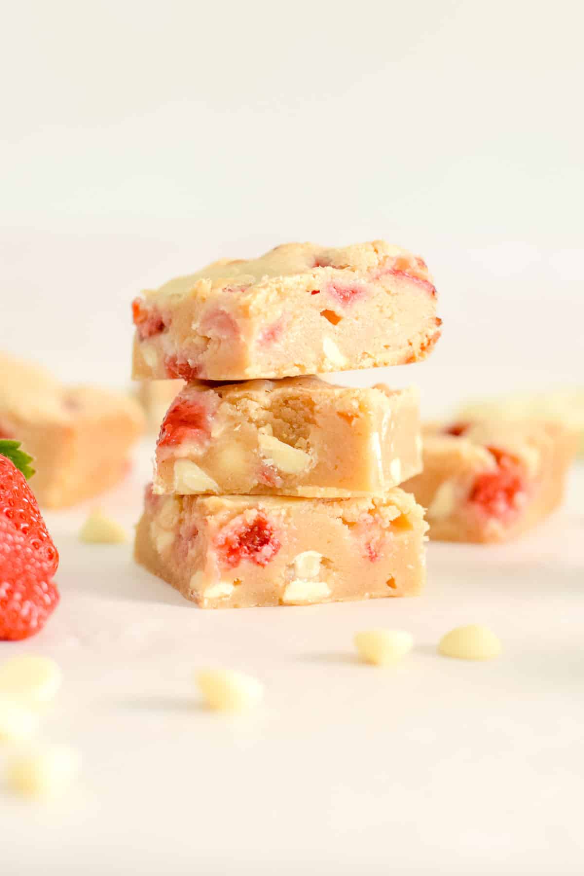 strawberry blondies with white chocolate chips and strawberries stacked in squares.